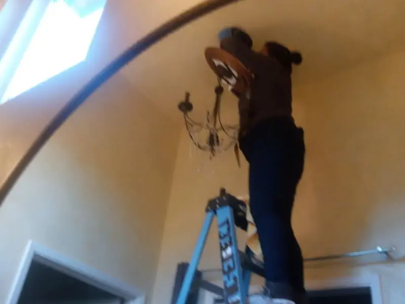 Electrician installing a chandelier in a Bithlo residence